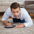 Professional male technician examining carpet with magnifying glass